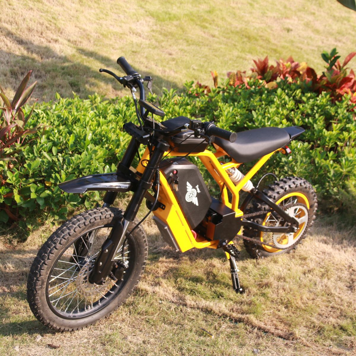 Yellow electric bike on a grassy area with plants in the background