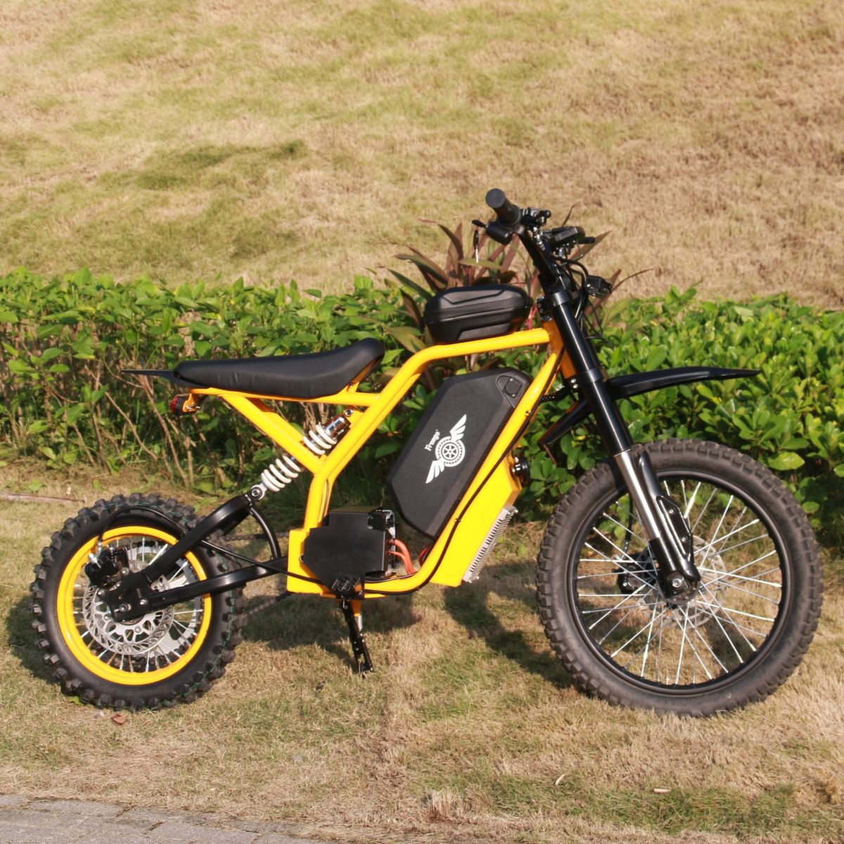 Yellow electric bike on a grassy area with plants in the background